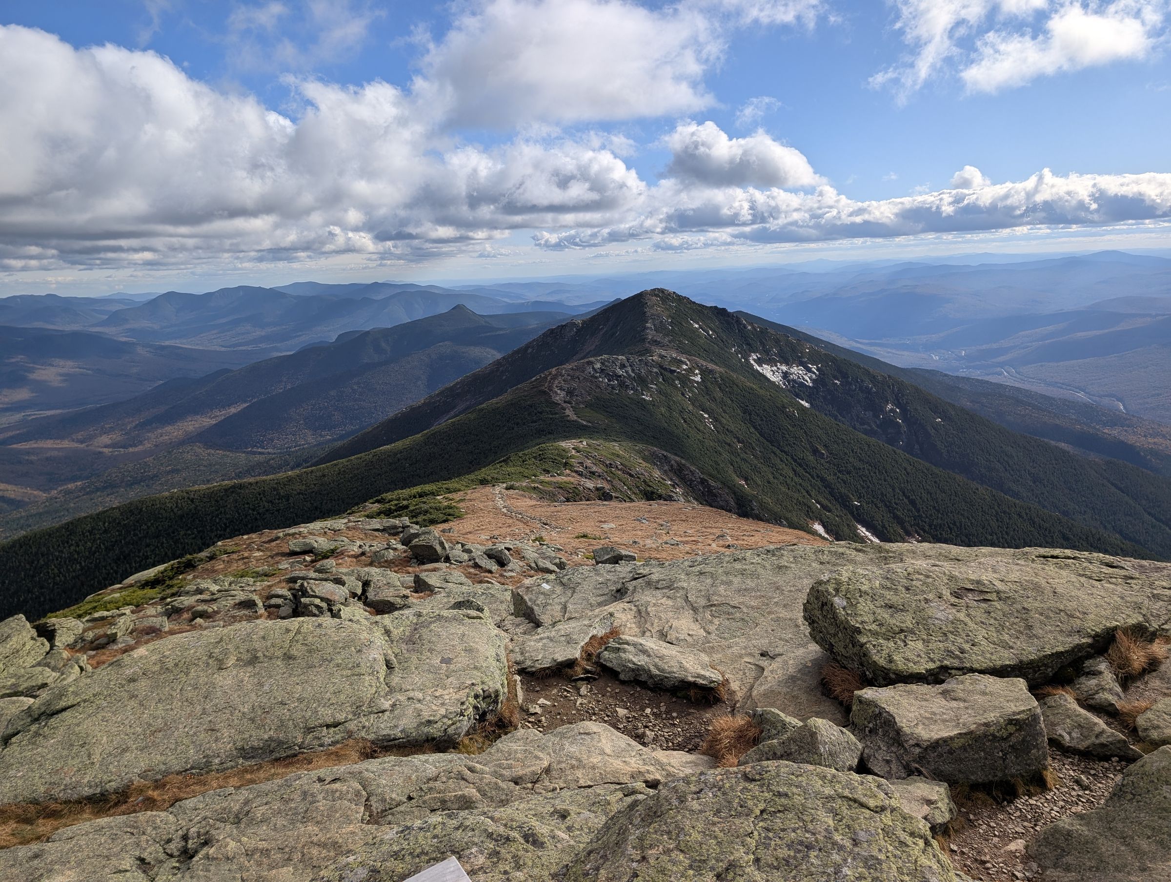 Alpine ridge trail stretching toward a distant peak under a partly cloudy sky